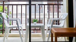 A balcony with two white plastic chairs and a small table with a potted plant. - Diamond Crown Hotel Patong (Patong)