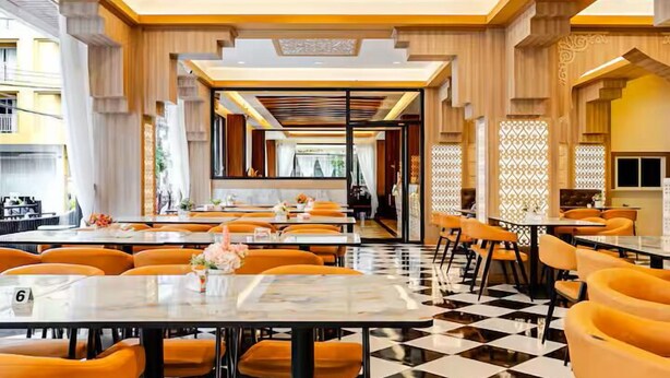 A restaurant with checkered flooring, orange chairs, and a checkered ceiling design. - Diamond Crown Hotel Patong (Patong)