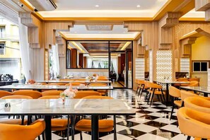 Un restaurante con piso a cuadros, sillas anaranjadas y un diseño de techo a cuadros.