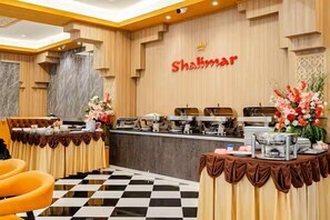 A reception area with a checkered floor, a counter with a nameplate, and a buffet setup. - Chana Phuket Patong Hotel (Patong)