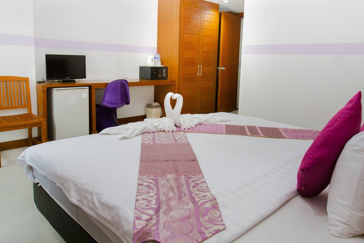 Une chambre d’hôtel comprenant un lit, un bureau avec un ordinateur, une chaise et une armoire.