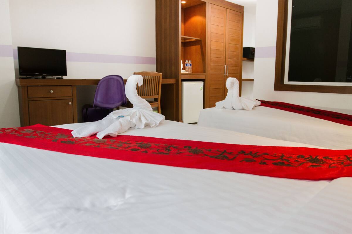 Une chambre d’hôtel comprenant un lit, un bureau avec une télévision, une armoire et une chaise.