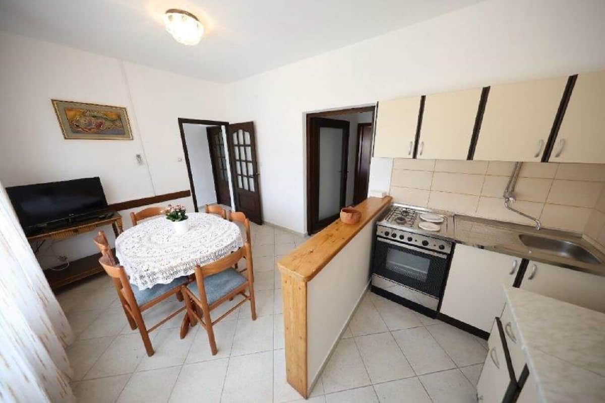 A compact kitchen with a dining table, a stove, and cabinets.