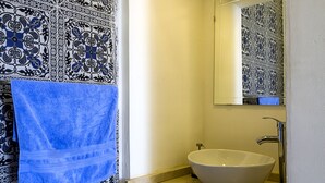 Une salle de bain avec un lavabo blanc, un miroir et une serviette bleue accrochée au mur.
