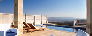A poolside area with lounge chairs and a view of distant mountains.