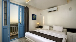 Une chambre d’hôtel avec un grand lit, une table de chevet, un appareil de climatisation, un tableau et un balcon avec vue.