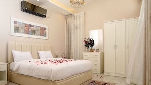 Ein Schlafzimmer mit einem Bett, Nachttisch, Schminktisch, Kleiderschrank und einem Wandbild.