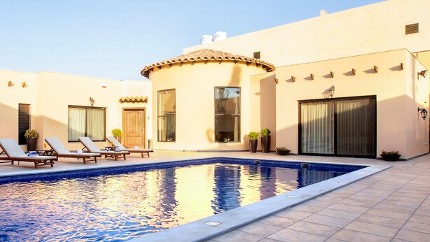 A swimming pool with lounge chairs and potted plants. - Villa Naya Branch 5 Saray (Al Rama)
