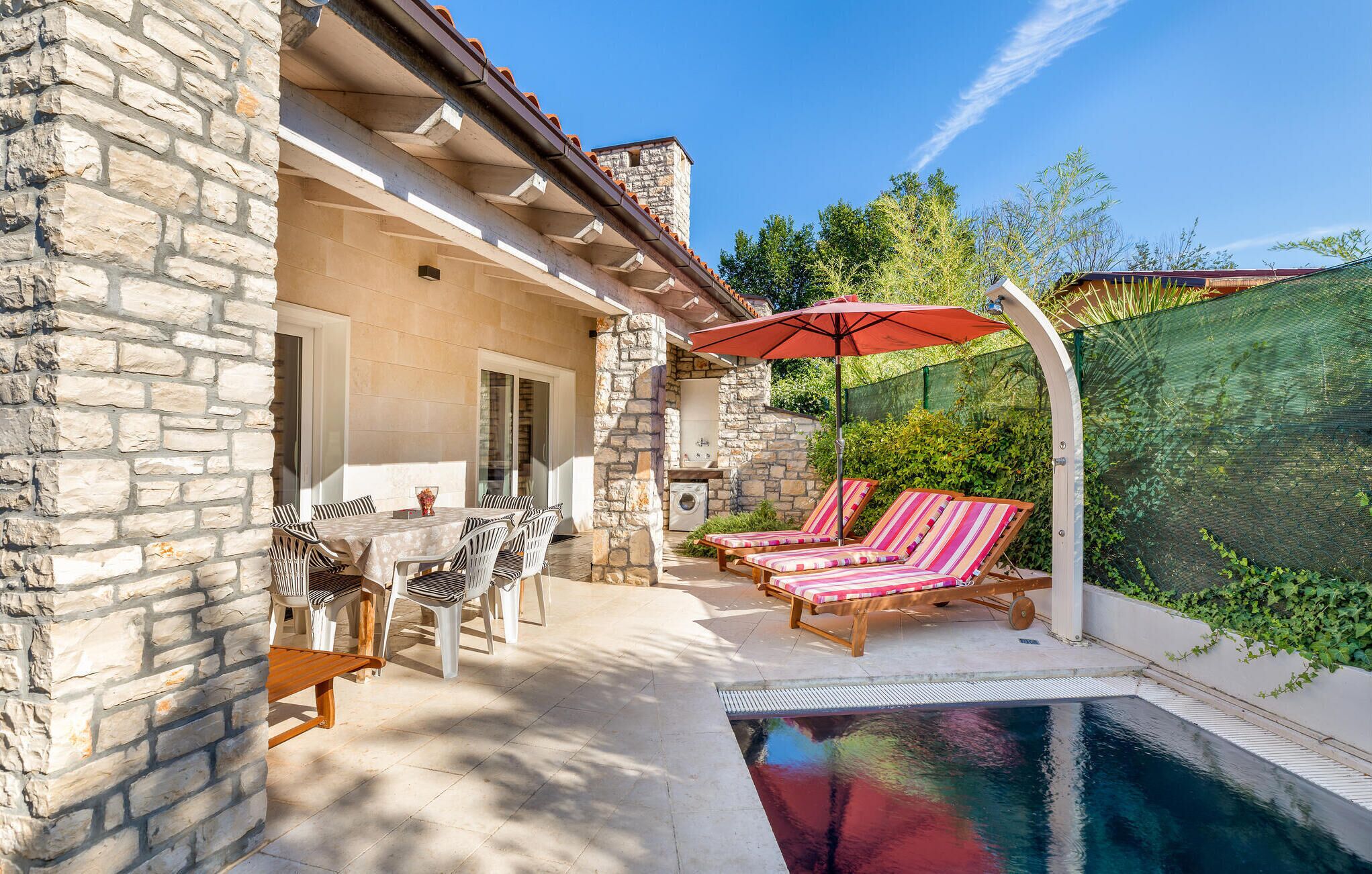 A stone building with a pool, outdoor seating, and a covered area.