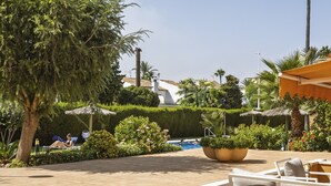 Uma área de piscina com espreguiçadeiras, um vaso grande e vista clara da piscina.
