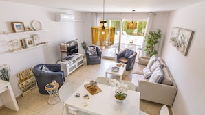 Uma sala de estar moderna com um sofá, cadeiras, uma mesa de jantar e uma televisão.