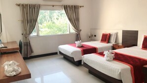 A hotel room with two beds, a wooden desk, and a window with curtains.