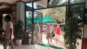 A hotel entrance with a tiled floor, potted plants, and a glass door leading outside.