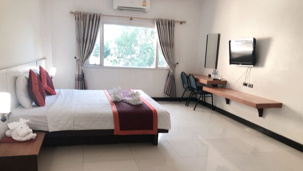 A hotel room with a bed, a desk, a chair, a TV, and a window with curtains.
