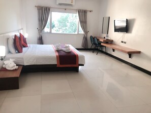 Une chambre d’hôtel avec un lit, un bureau, une chaise, une télévision et une fenêtre avec des rideaux.