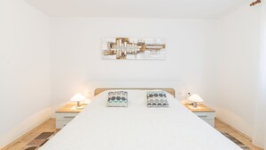 Une chambre à coucher avec un grand lit, deux tables de chevet avec des lampes et une œuvre d’art murale au-dessus du lit.