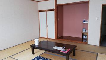 A traditional Japanese room with tatami flooring, a low wooden table, a blue cushion, and sliding doors.