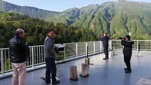 Un grupo de personas en una azotea con vistas a montañas verdes.