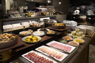 Un buffet proposant une variété de plats, notamment des viandes, des légumes et des desserts.