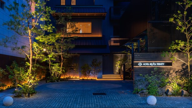 A modern hotel entrance with a well-lit pathway, a stone sphere, and a sign for Hotel Resol Trinity. - Resol Hotel Trinity Osaka (Osaka)