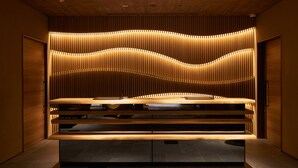 A modern interior with a central wooden table and tiered seating. - Resol Hotel Trinity Osaka (Osaka)