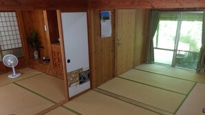 Ett traditionellt japanskt rum med tatamimattor på golvet, en shojiskärm, en fläkt och en kalender på dörren.