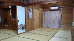 Ett traditionellt japanskt rum med tatamimattor på golvet, en trädörr, en kalender och en liten krukväxt.