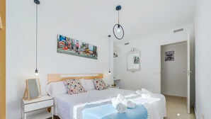 Una habitación de hotel con cama, mesita de noche y un cuadro colgado en la pared.