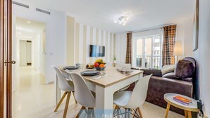 Una sala de estar moderna con comedor, que incluye un televisor de pantalla plana, un sofá y una pequeña mesa con una libreta.