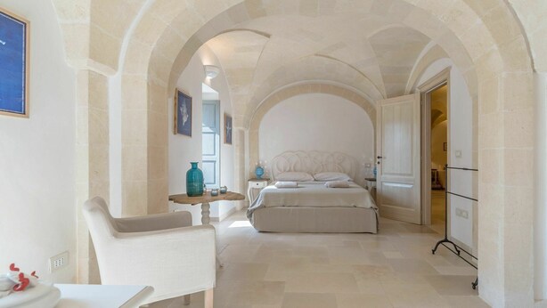 A bedroom with a bed, a chair, a table, and a door leading to another room. - Villa in Ostuni with 4 bedrooms sleeps 8 (Ostuni)