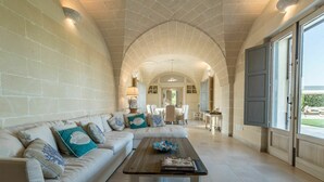 A spacious living room with a white sofa, a wooden coffee table, and a view of the outdoors through a large window. - Villa in Ostuni with 4 bedrooms sleeps 8 (Ostuni)