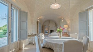 A dining area with a round table, chairs, a vase with flowers, and a lamp on a side table. - Villa in Ostuni with 4 bedrooms sleeps 8 (Ostuni)