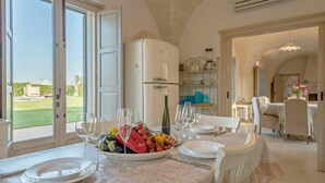 A dining area with a table set for six, a refrigerator, and a view of the outdoors. - Villa in Ostuni with 4 bedrooms sleeps 8 (Ostuni)