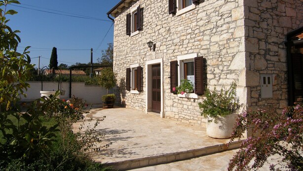 A stone building with a door and two windows, surrounded by potted plants and greenery. - Villa Ana - Peaceful Location (Marcana)