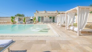 A pool area with lounge chairs and a covered seating area.