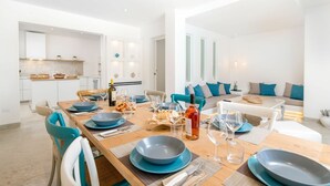 A modern dining area with a wooden table set for six, blue plates, and wine glasses.