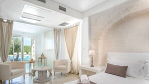 A hotel room with a bed, a round table, two chairs, a lamp, and a view of a pool.