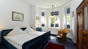 A bedroom with a bed, a nightstand, a chair, and a wardrobe.