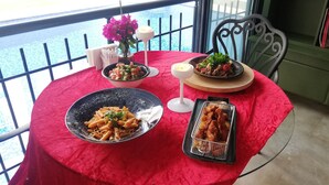 Een tafel met een rode tafelkleed, een schaal pasta, een schaal salade, een bord met groenten en een dienblad met gefrituurde snacks.