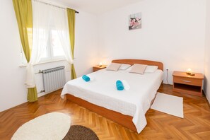 A neatly arranged bedroom with a bed, two bedside tables, a radiator, and a window with curtains. - Family house with 2 apartments - Irma (Medulin)