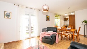A living room with a sofa, a dining table with chairs, a kitchen area, and a balcony with a sliding door. - Family house with 2 apartments - Irma (Medulin)