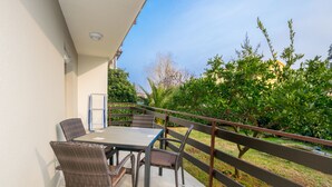 A balcony with a table and chairs, surrounded by greenery and a railing. - Family house with 2 apartments - Irma (Medulin)