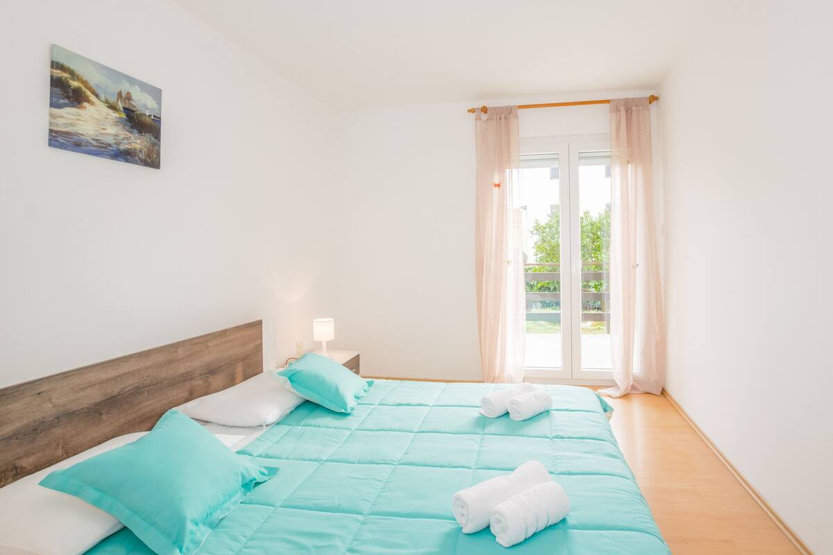 Ein Schlafzimmer mit einem Bett, Kissen, einem Nachttisch und einem Bild an der Wand.