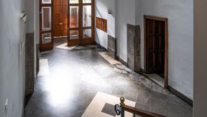 Um corredor com porta de madeira, escada e pequena janela.