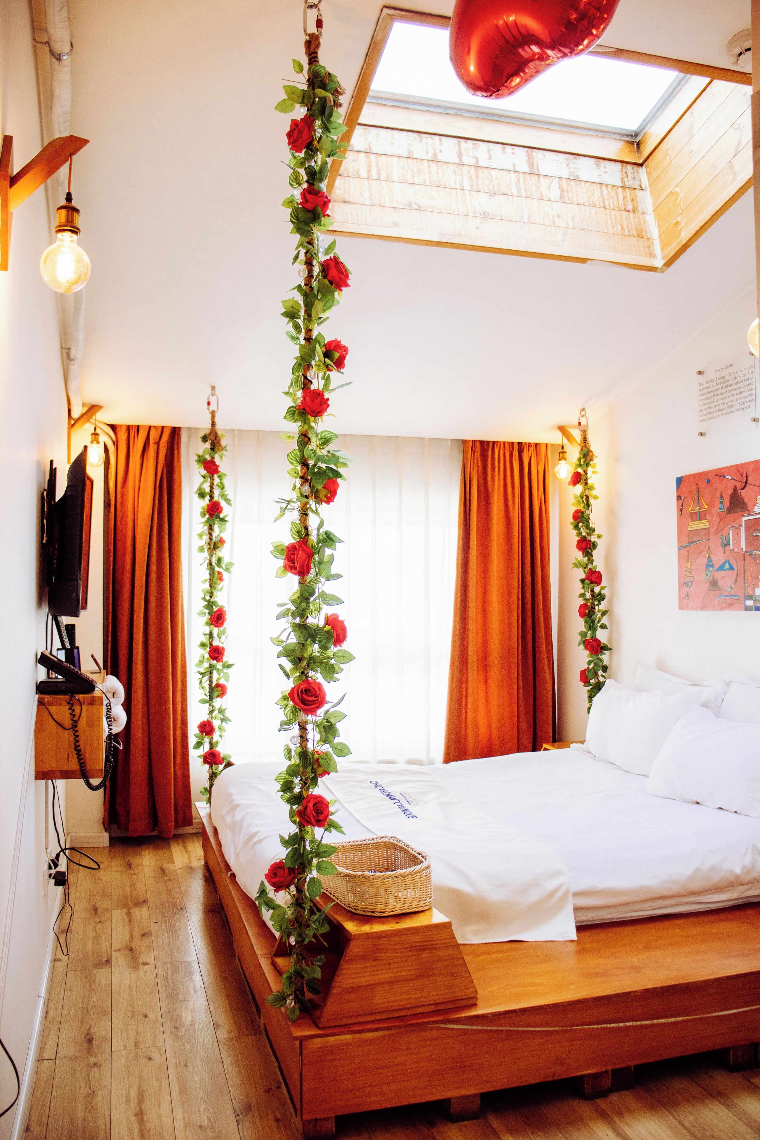 A bedroom with a wooden bed, a skylight, and a red balloon.