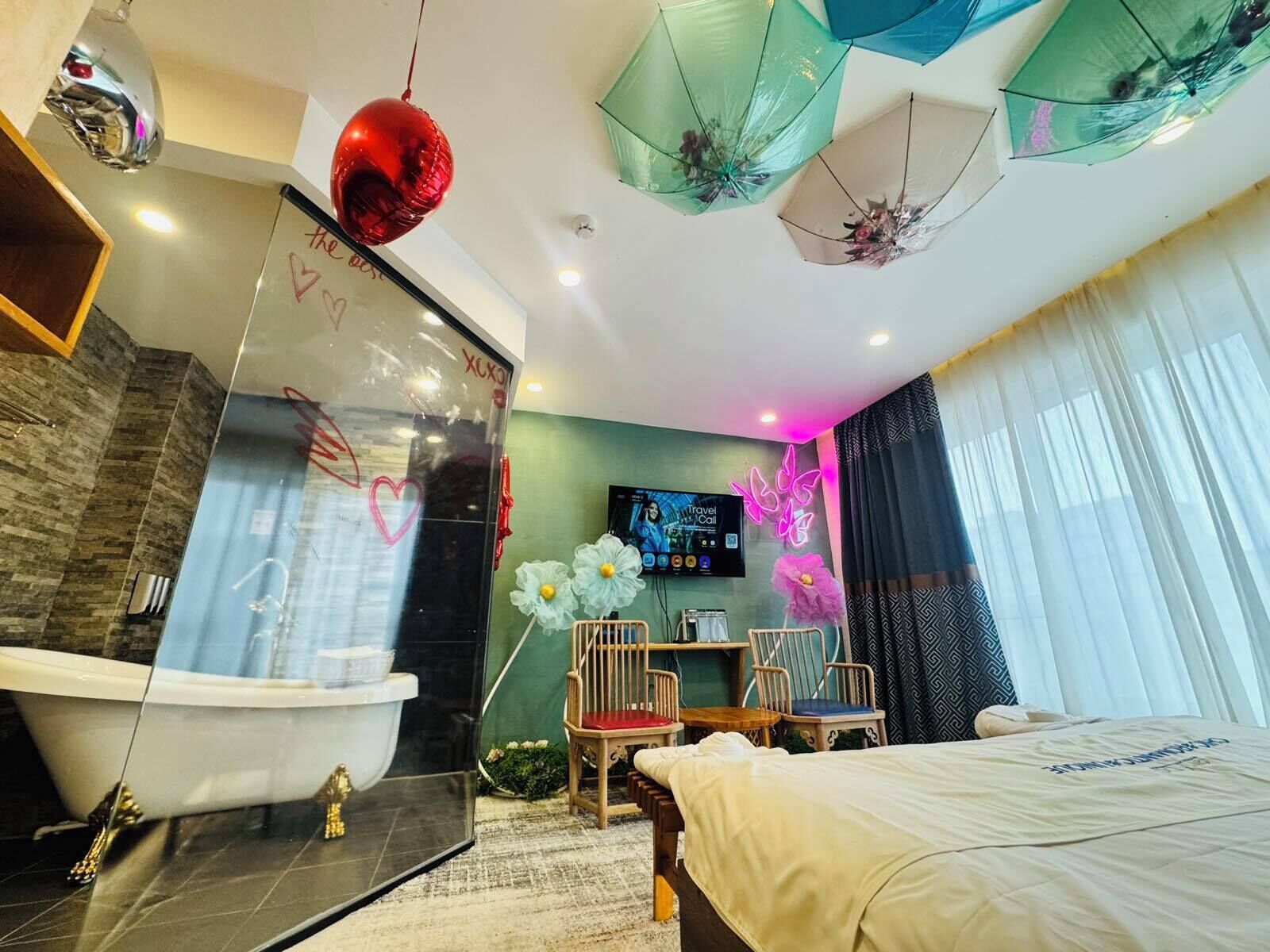 A modern hotel room with a bathtub, a bed, a desk, and a TV.