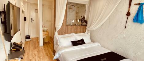 A modern bedroom with a canopy bed, a wooden bench, a cowhide rug, a mirror, and a television.