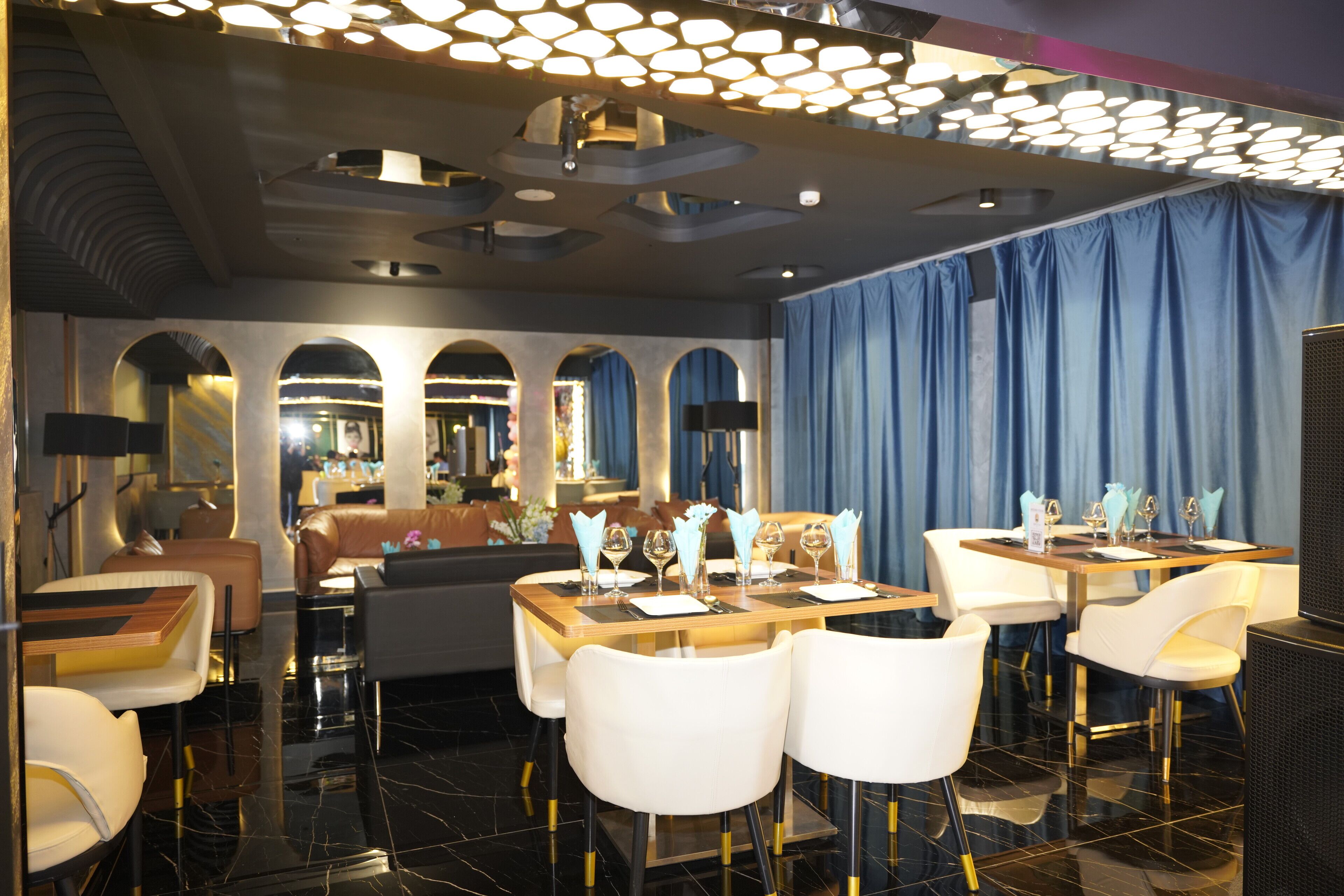 Un restaurant au décor moderne, comprenant une salle à manger avec des tables et des chaises, un bar et un espace détente avec un canapé et des fauteuils.