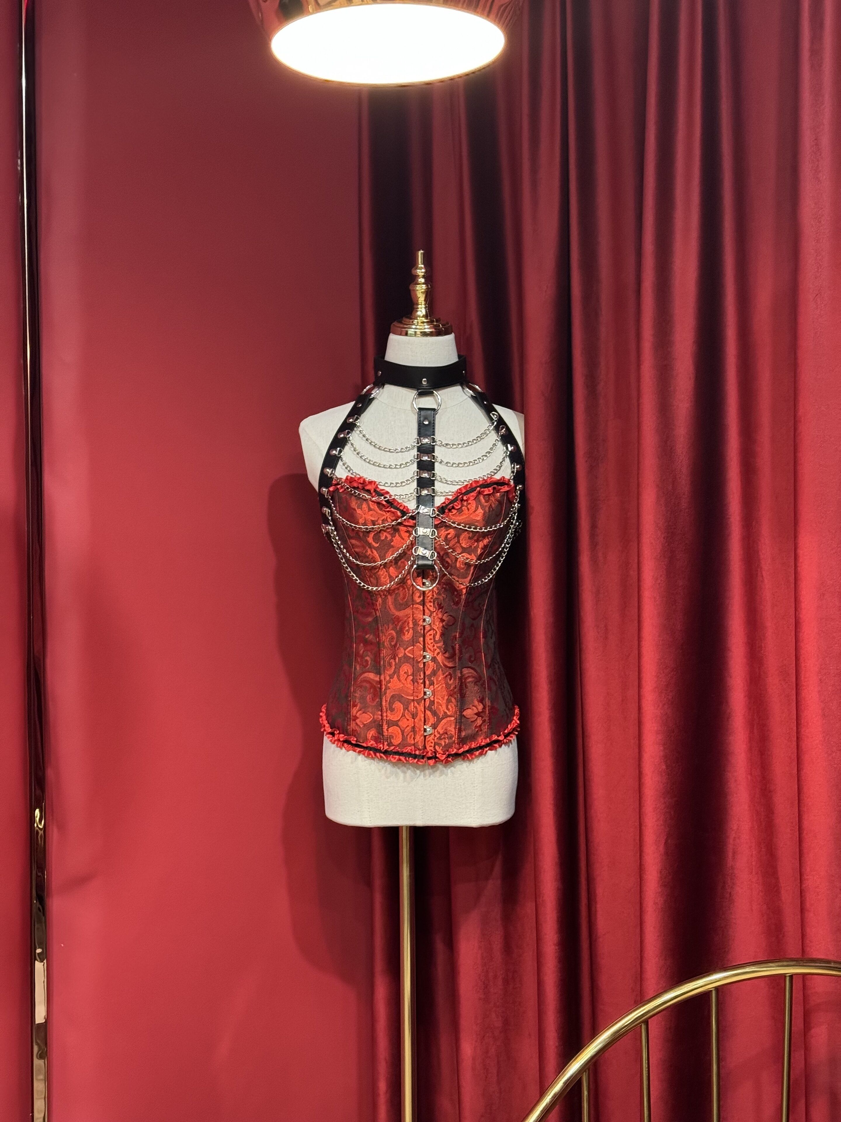 Un maniquí vestido con un corpiño estampado con motivos florales, frente a un telón rojo.