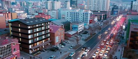 A multi-story hotel with a prominent sign, a restaurant, and a parking lot with cars.
